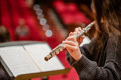 Student playing a flute looking at music sheet.